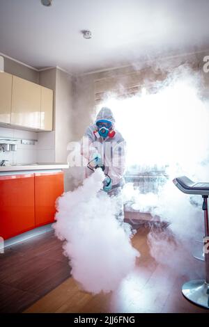 Desinfektion des Raumes gegen Viren. Mann in Quarantänekleidung, der den Raum desinfiziert. Stockfoto