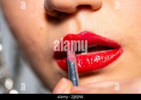 Nahaufnahme einer Frau, die einen roten Lippenstift aufgibt Stockfoto