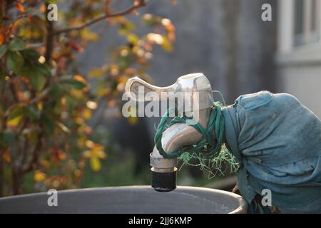 Eine Nahaufnahme eines rostigen alten Wasserhahns mit Seil in einem Garten Stockfoto