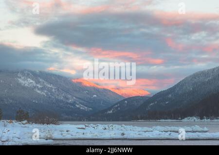 Sonnenaufgang oder Sonnenuntergang am Kootenay See mit Schnee und Bergen in Nelson, British Columbia, Kanada im Winter. Stockfoto