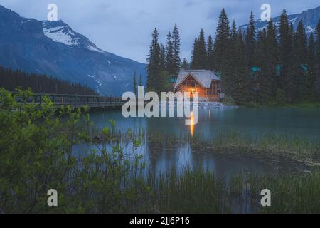 Emerald Lake, Kanada - 30. Juni 2022: Stimmungsvolles goldenes Licht aus der traditionellen Blockhütte Emerald Lake Lodge in der Nacht in den Rocky Mountains in Yoh Stockfoto