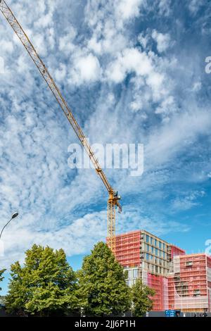 Eine vertikale Aufnahme eines großen Krans ragt über einer Baustelle unter bewölktem Himmel Stockfoto