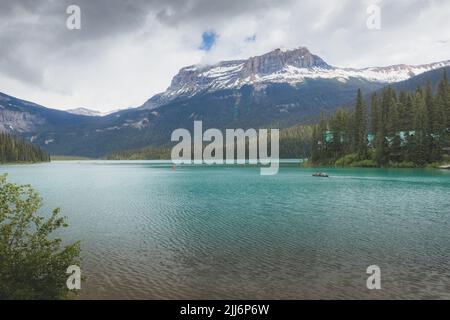 Berglandschaft und Touristen in bunten roten Kanus während eines friedlichen Morgens auf Emerald Lake im Yoho Nationalpark, in British Columbia, Kanada. Stockfoto