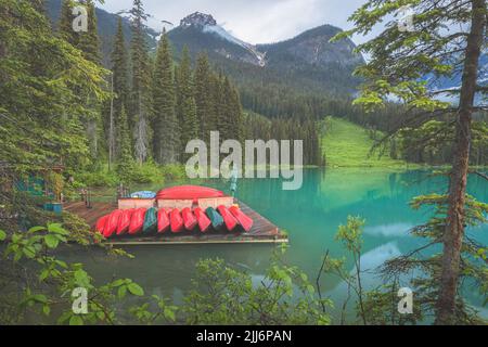 Berglandschaft und farbenfrohe rote Kanus auf einem Dock während eines ruhigen, ruhigen, friedlichen Morgens am Emerald Lake im Yoho National Park, in British Columbi Stockfoto