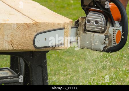 Ein Bauarbeiter schneidet Bretter mit einer Kettensäge in der Konstruktion. Konzentrieren Sie sich auf Kettensäge Stockfoto