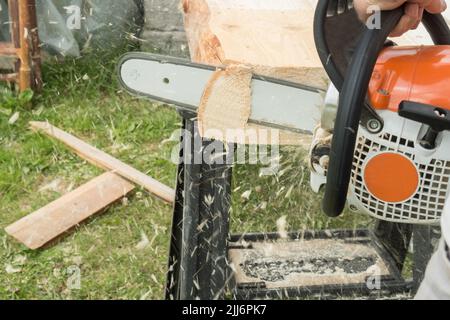 Ein Bauarbeiter schneidet Bretter mit einer Kettensäge in der Konstruktion. Konzentrieren Sie sich auf Kettensäge Stockfoto