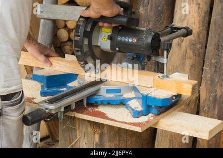 Zimmermann schneidet Holz mit einer Gehrungs- oder Kreissäge Stockfoto