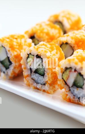 Eine vertikale Aufnahme leckerer Sushi-Rollen auf einem weißen Teller Stockfoto