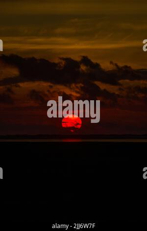 Eine vertikale Aufnahme des goldenen Sonnenuntergangs am dunklen Himmel Stockfoto