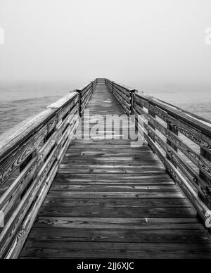 Holzsteg im Meer an nebeligen Morgen Stockfoto