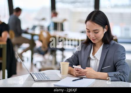 Junge asiatische Geschäftsfrau mit Smartphone bei der Arbeit. Banner Stockfoto