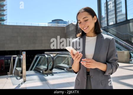 Junge glückliche asiatische Geschäftsfrau, die mit dem Smartphone in der U-Bahn der Stadt steht. Stockfoto