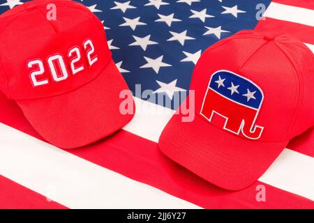 Rote MAGA-Mütze mit 2022 und republikanischer Elefant- und US-Stars and Stripes-Flagge. Für die Mittelfristwahlen in den USA im November 2022 und die republikanische Rote Welle. Stockfoto