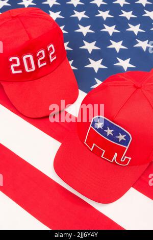 Rote MAGA-Mütze mit 2022 und republikanischer Elefant- und US-Stars and Stripes-Flagge. Für die Mittelfristwahlen in den USA im November 2022 und die republikanische Rote Welle. Stockfoto