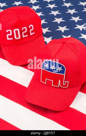 Rote MAGA-Mütze mit 2022 und republikanischer Elefant- und US-Stars and Stripes-Flagge. Für die Mittelfristwahlen in den USA im November 2022 und die republikanische Rote Welle. Stockfoto