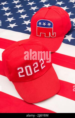 Rote MAGA-Mütze mit 2022 und republikanischer Elefant- und US-Stars and Stripes-Flagge. Für die Mittelfristwahlen in den USA im November 2022 und die republikanische Rote Welle. Stockfoto