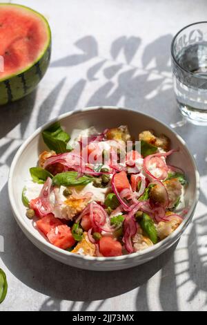 Sommersalat mit Wassermelone, Buratta, Basilikum und eingelegten Zwiebeln Stockfoto