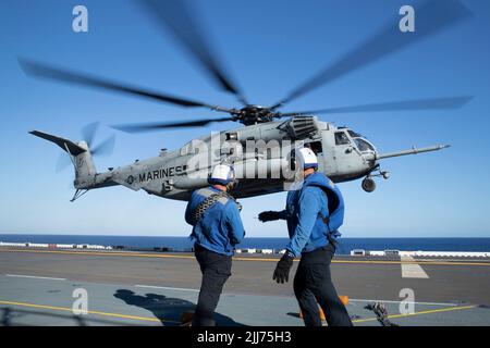220722-N-XN177-2092 PAZIFISCHER OZEAN (22. Juli 2022) – Matrosen stellen sich gegen die Rotorwäsche ein, da ein CH-53 Super Hengst-Hubschrauber, der Marine Medium Tiltrotor Squadron (VMM) 262 (verstärkt) zugewiesen wurde, an Bord des amphibischen Angriffsträgers USS Tripoli (LHA 7) auf dem Flugdeck landet, 22. Juli 2022. Tripolis ist im Einsatzgebiet der US-Flotte von 7. tätig, um die Interoperabilität mit Verbündeten und Partnern zu verbessern und als einsatzbereite Einsatztruppe für den Frieden und die Stabilität in der Region Indo-Pazifik zu dienen. (USA Navy Foto von Mass Communication Specialist 1. Klasse Peter Burghart) Stockfoto