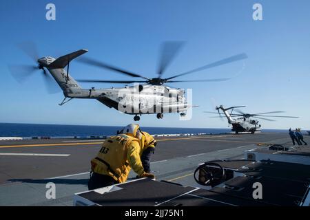 220722-N-XN177-2050 PAZIFISCHER OZEAN (22. Juli 2022) – Matrosen stellen sich gegen die Rotorwäsche ein, da ein CH-53 Super Hengst-Hubschrauber, der Marine Medium Tiltrotor Squadron (VMM) 262 (verstärkt) zugewiesen wurde, an Bord des amphibischen Angriffsträgers USS Tripoli (LHA 7) auf dem Flugdeck landet, 22. Juli 2022. Tripolis ist im Einsatzgebiet der US-Flotte von 7. tätig, um die Interoperabilität mit Verbündeten und Partnern zu verbessern und als einsatzbereite Einsatztruppe für den Frieden und die Stabilität in der Region Indo-Pazifik zu dienen. (USA Navy Foto von Mass Communication Specialist 1. Klasse Peter Burghart) Stockfoto