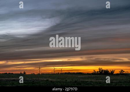 Die Silhouette mehrerer moderner Windmühlen am niedrigen Horizont bei einem bunten Sonnenuntergang, außerhalb von Kiyú, San José, Uruguay Stockfoto