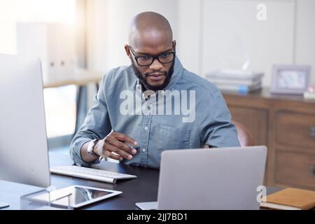 Vorbereitung auf einen großen Tag. Ein junger Geschäftsmann mit einem Laptop in einem Büro bei der Arbeit. Stockfoto