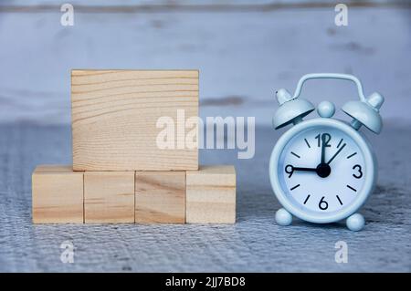 Leere Holzblöcke und Wecker mit anpassbarem Raum für Ideen oder Text. Speicherplatz kopieren Stockfoto