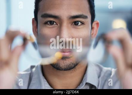 Es ist meine Aufgabe, Ihnen die Dinge so klar wie möglich zu machen. Ein hübscher junger Geschäftsmann sitzt allein im Büro und hält seine Brille. Stockfoto