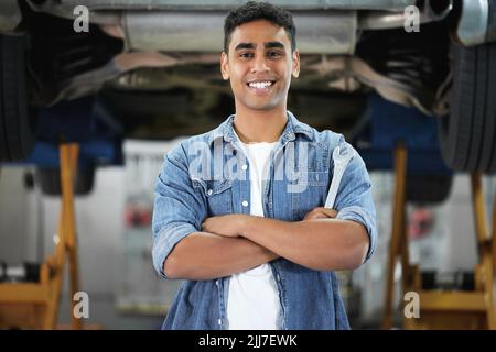 Hes hat dir den Rücken gekehrt. Porträt eines hübschen jungen Mechanikers, der mit gefalteten Armen in seiner Werkstatt steht. Stockfoto