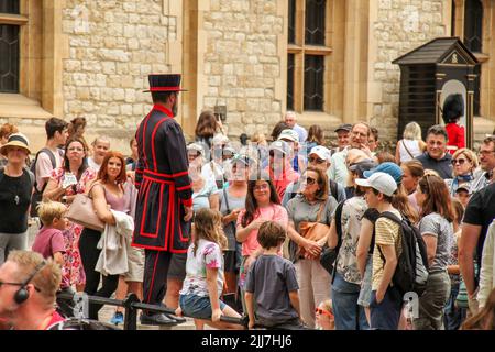 London, Großbritannien. 22.. Juli 2022. Ein Yeoman Warder unterzieht sich mit Besuchern während einer Tour durch den Tower of London. Der Turm, der sich nördlich der Themse befindet, diente als Waffenlager, Schatzkammer, Heimat der Royal Mint und der Kronjuwelen Englands. Kredit: SOPA Images Limited/Alamy Live Nachrichten Stockfoto