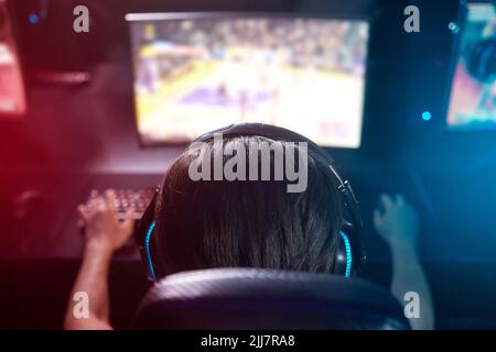 Sport treiben, ohne den Sitz zu verlassen. Rückansicht eines jungen Mannes, der Computerspiele spielt. Stockfoto