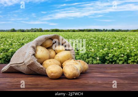 Junge Kartoffeln im Sackleinen auf Holztisch Stockfoto