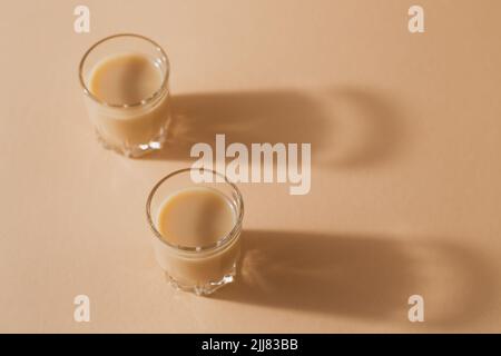 Kurze Gläser Irish Cream Liquor oder Coffee Liqueur auf hellbeigem Hintergrund Stockfoto