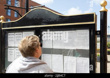 Junge Frauen, die Städte betrachten, bemerken an Bord selektive Fokusdokumente verschwommener Kopierraum an Bord des Informationskonzepts Stockfoto