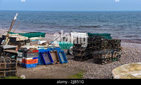 Angelausrüstung am Steinstrand von Budleigh Salterton in Devon gelagert. Töpfe, Netze, Schalen, Boote, Ruten, Seil jeden Tag ordentlich gelagert. Stockfoto