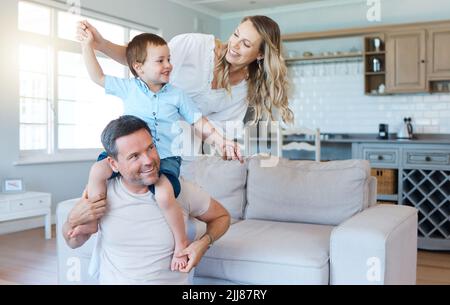 Als Familie bedeutet, dass Sie ein Teil von etwas sind. Zwei Eltern spielen mit ihrem Sohn zu Hause. Stockfoto