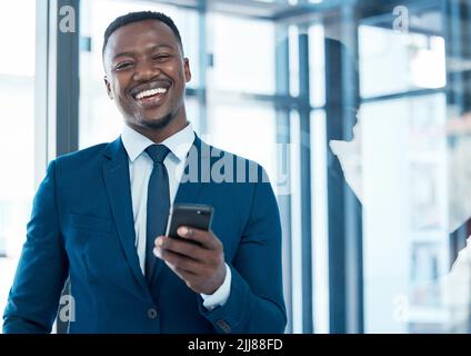 Ich habe einige gute Nachrichten mit Ihnen zu teilen. Ein junger Geschäftsmann mit einem Smartphone in einem modernen Büro. Stockfoto