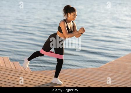 Aktive schwarze Frau beim Training im Freien, mit Widerstandsband Stockfoto