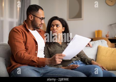 Besorgetes Afrikanisches Paar, Das Papiere Hält, Rechnungen Liest, Die Probleme Im Innen Haben Stockfoto