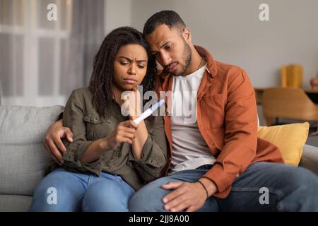 Depressive Schwarze Paar Hält Negative Schwangerschaft Test Sitzen Zu Hause Stockfoto