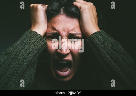 Ist das alles in deinem Kopf? Studioaufnahme einer jungen Frau, die vor schwarzem Hintergrund psychische Qualen und Schreie erlebt. Stockfoto