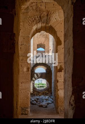 Ein Blick entlang eines Durchgangs innerhalb der hoch aufragenden Ruinen des riesigen römischen Amphitheaters in El Jem, Tunesien. Stockfoto