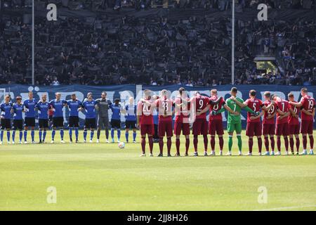 24. Juli 2022, Nordrhein-Westfalen, Bielefeld: Fußball: 2. Bundesliga, Arminia Bielefeld - Jahn Regensburg, Matchday 2 in der Schüco Arena. Die Teams von Bielefeld (blau) und Regensburg (rot) gedenken mit einer Schweigeminute vor Spielbeginn dem verstorbenen Fußball-Ikone Uwe Seeler. Foto: Friso Gentsch/dpa - WICHTIGER HINWEIS: Gemäß den Anforderungen der DFL Deutsche Fußball Liga und des DFB Deutscher Fußball-Bund ist es untersagt, im Stadion und/oder vom Spiel aufgenommene Fotos in Form von Sequenzbildern und/oder videoähnlichen Fotoserien zu verwenden oder zu verwenden. Stockfoto