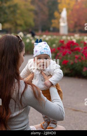 Junge Mutter hält unschuldiges Baby in liebevollen Händen draußen Stockfoto