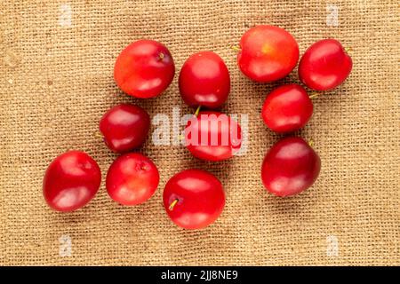 Mehrere Bio-Kirschpflaumen auf Jute-Stoff, Nahaufnahme, Draufsicht. Stockfoto