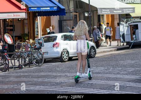 PARIS / FRANKREICH - 28. JUNI 2019: Ein junges, wunderschönes blondes Mädchen, das in den Straßen von Paris, Frankreich, auf einem Elektro-Kick-Scooter reitet Stockfoto