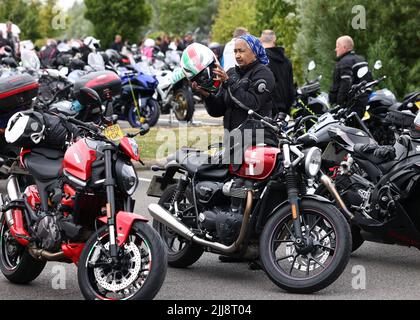 Hinckley, Leicestershire, Großbritannien. 24.. Juli 2022. Eine Fahrerin setzt ihren Sturzhelm während eines Weltrekordversuchs für das größte Biker-Treffen der Frauen am globalen Hauptsitz von Triumph Motorcycles an. Credit Darren Staples/Alamy Live News. Stockfoto