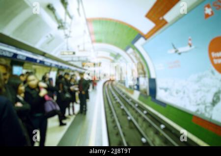 Verschwommener Blick auf die Menschenmenge auf dem Bahnsteig der geschäftigen U-Bahn-Station in London. Perspektivische Ansicht. Für den Hintergrund des Reisekonzepts verwenden. Stockfoto