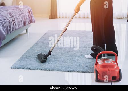 Hausfrau Reinigung Staub das Haus Saugen Sie den Teppich im Schlafzimmer in den Morgen. Maid mit Technologie sauber Haus Housekeeping Konzept. Stockfoto