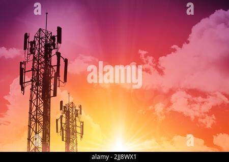 5G Kommunikationsturm oder 4G-Netzwerk-Telefon-Handy-Silhouette auf sonnigen bunten Himmel Hintergrund. Stockfoto
