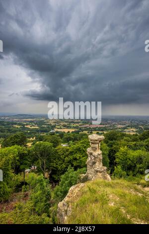 The Devil's Chimney auf dem Leckhampton Hill mit einem sich nähernden Gewitter über Cheltenham Spa, Gloucestershire, England Stockfoto